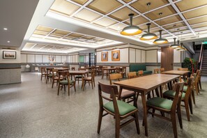 A spacious dining area with wooden tables and chairs, a high ceiling with recessed lighting, and framed artwork on the walls. - A Memory Hotel -Beijing Daxing (Daxing)