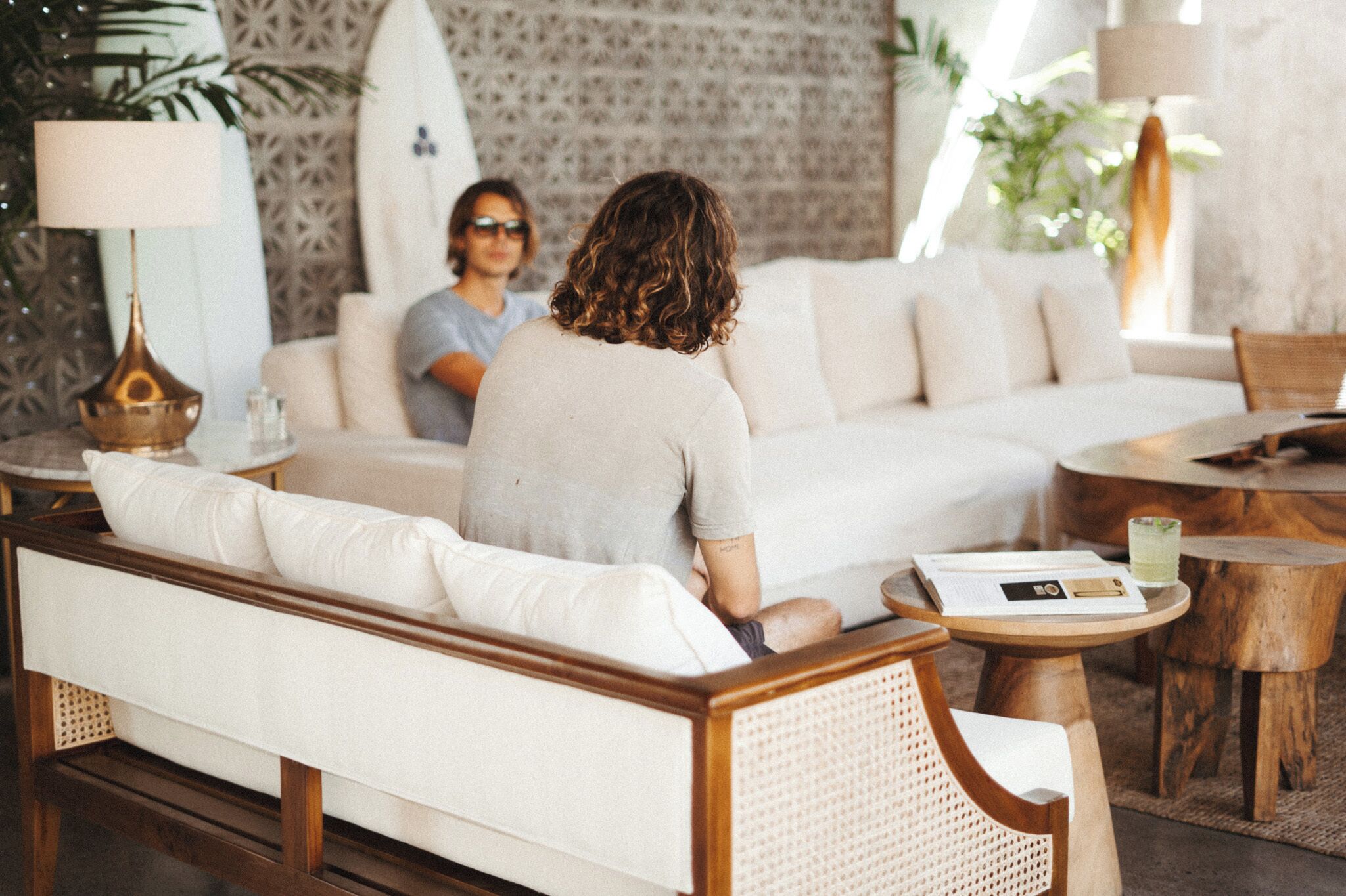 Een moderne woonkamer met een bank, een houten bijzettafeltje en een surfplank.