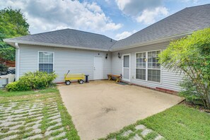 Une maison d’habitation dotée d’un patio couvert, d’un petit jardin et d’un banc en bois.
