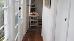 Un couloir étroit avec un plancher en bois, des portes blanches et un luminaire au plafond.