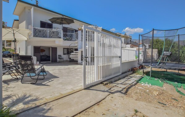 A two-story house with a balcony, a gated entrance, and a trampoline in the backyard.