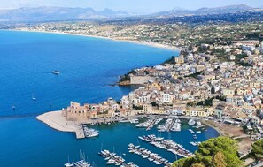 A coastal town with a marina filled with boats, historic buildings, and a beach.