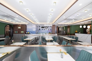 Un restaurant moderne doté d’un bar central, de coins salons et offrant une vue sur les montagnes.