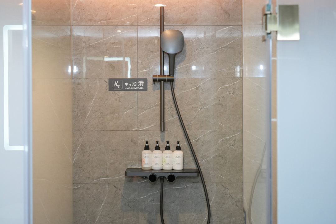 Una ducha con cabezal de ducha de mano y panel de control en la pared.