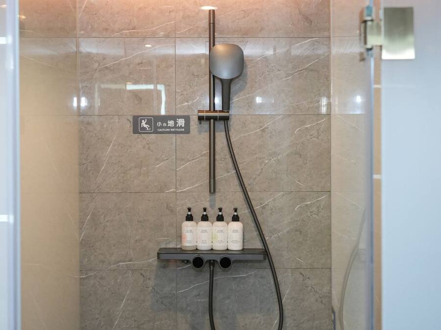 Una ducha con cabezal de ducha de mano y panel de control en la pared.