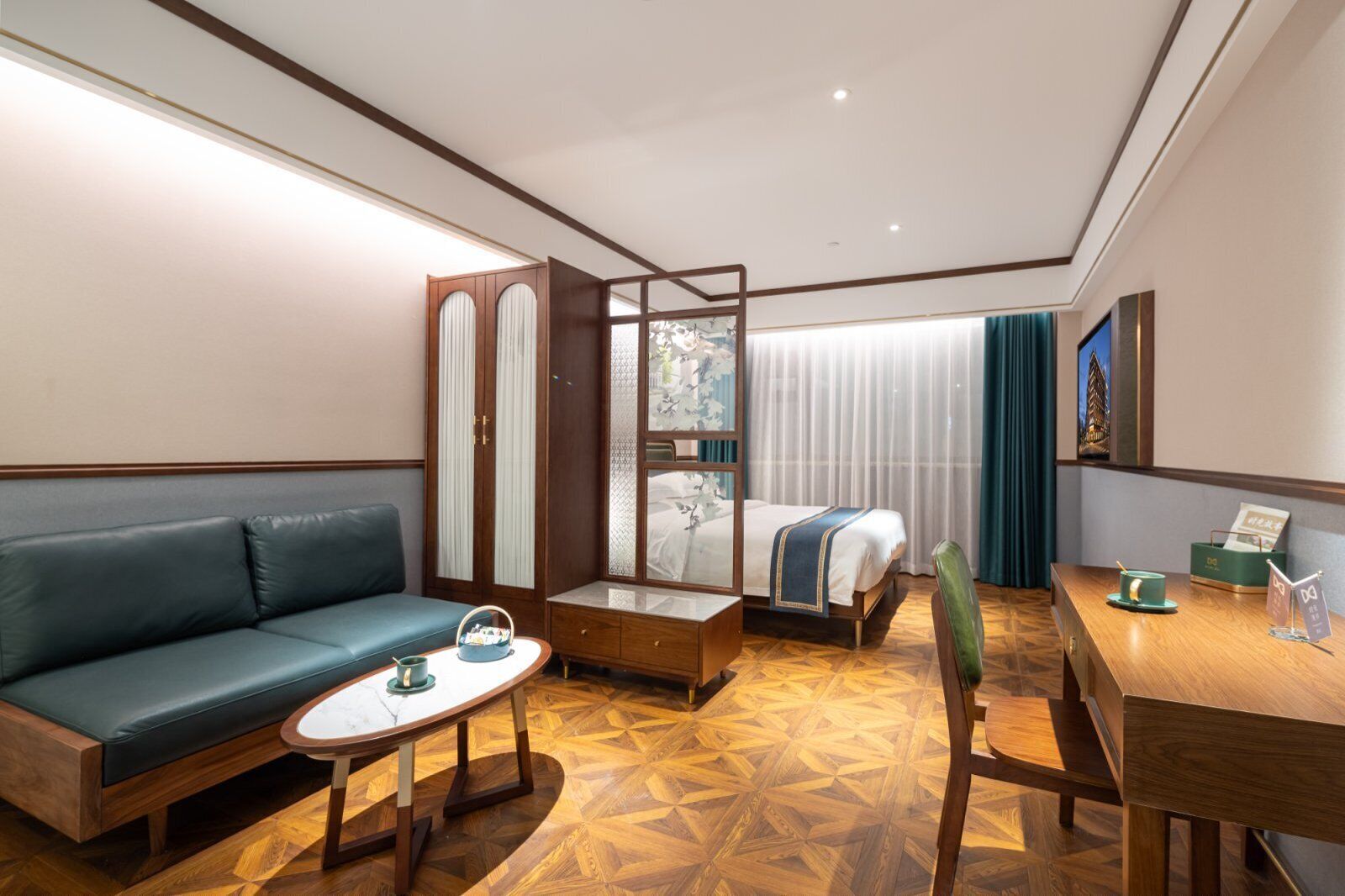 A hotel room with a sofa, a bed, a wooden desk, a small table, and a chair.