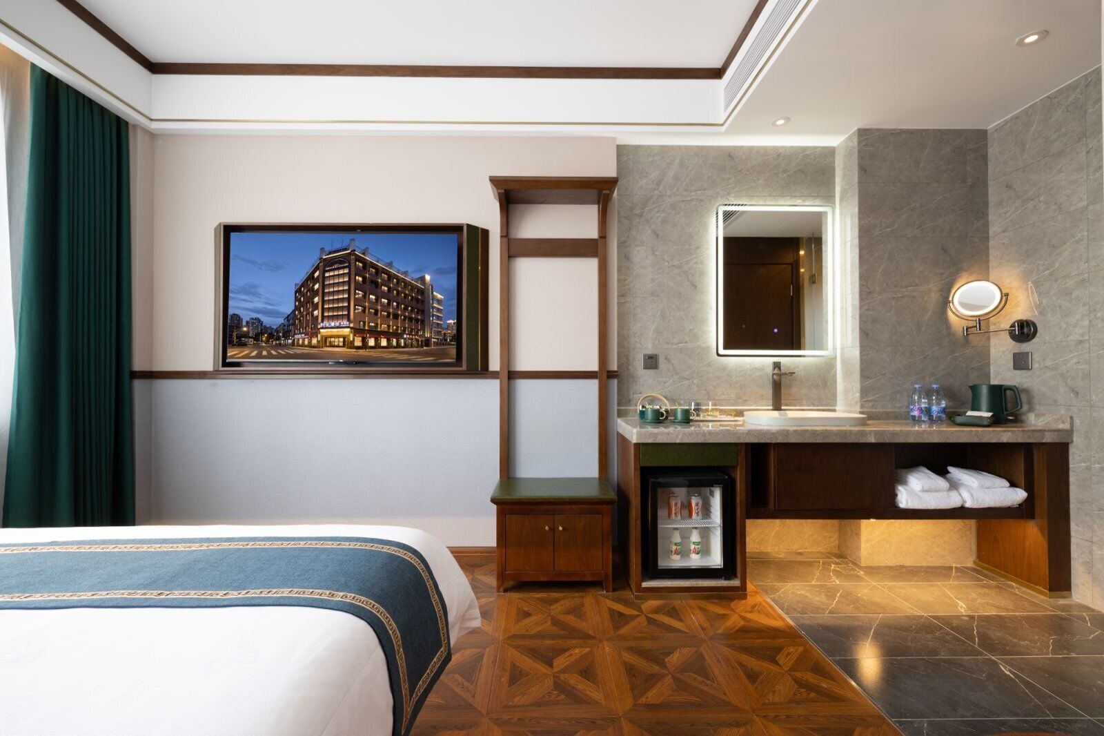 Habitación de hotel con cama, baño con espejo, lavamanos y un refrigerador pequeño.