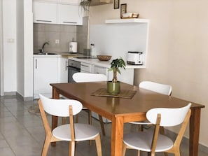 A modern kitchen with white cabinets, a wooden dining table, and white chairs. - Superior Onebedroom Apartment (Ulcinj)