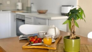 A breakfast setup with a tray of strawberries, a glass of orange juice, and a green mug on a wooden table.