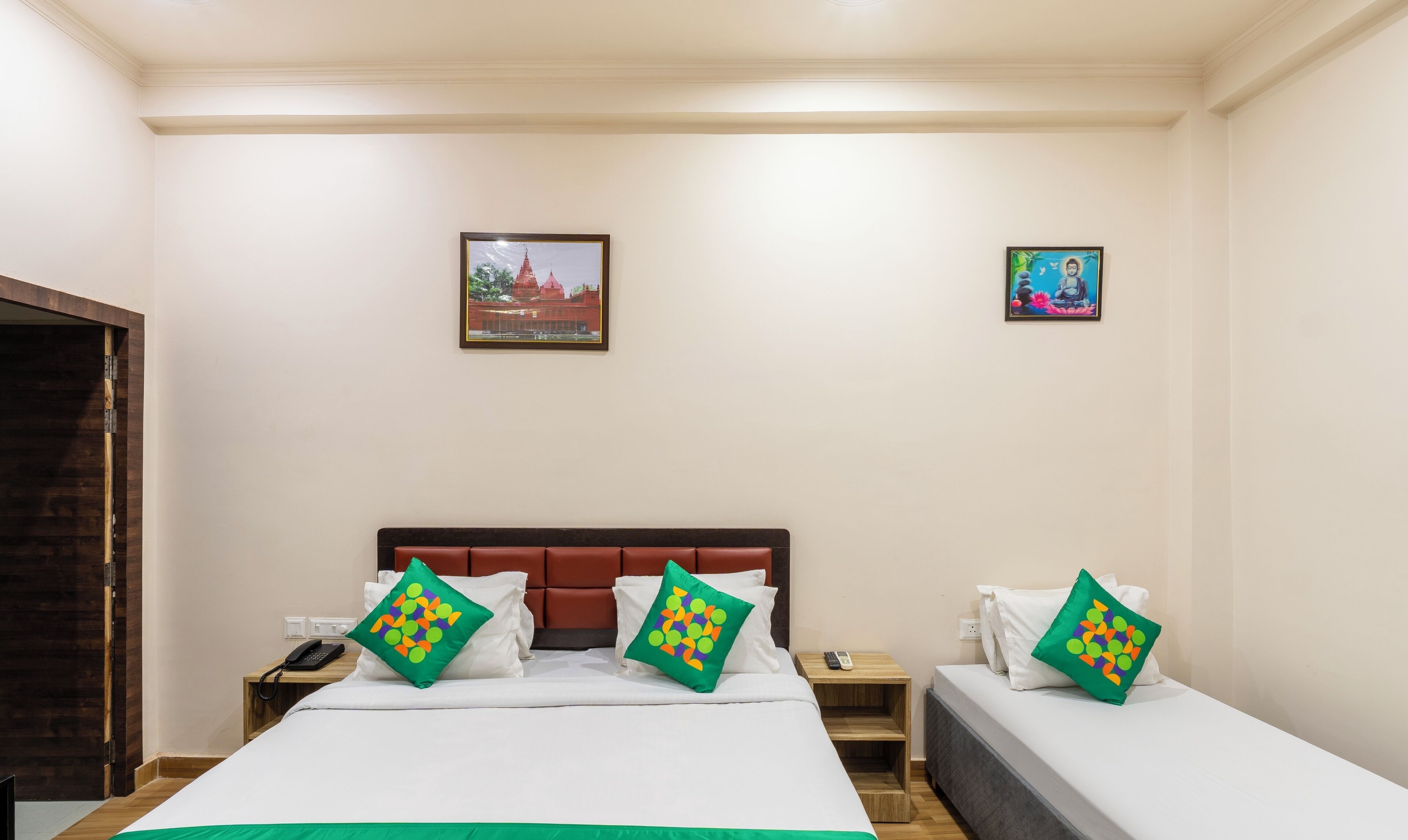 A hotel room with two beds, a wooden door, and two nightstands.