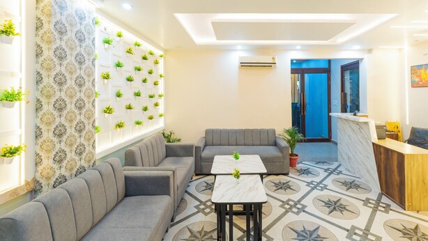 A modern interior with a sectional sofa, a small table, and a patterned floor. - Treebo Om Shree Banaras (Varanasi)