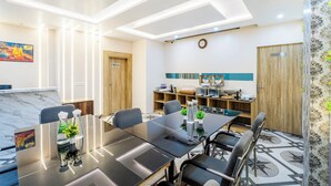 A modern conference room with a marble reception desk, a buffet area, and a clock on the wall. - Treebo Om Shree Banaras (Varanasi)