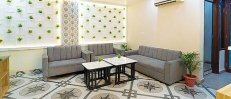 A modern lounge area with grey sofas, a marble coffee table, and patterned floor tiles.