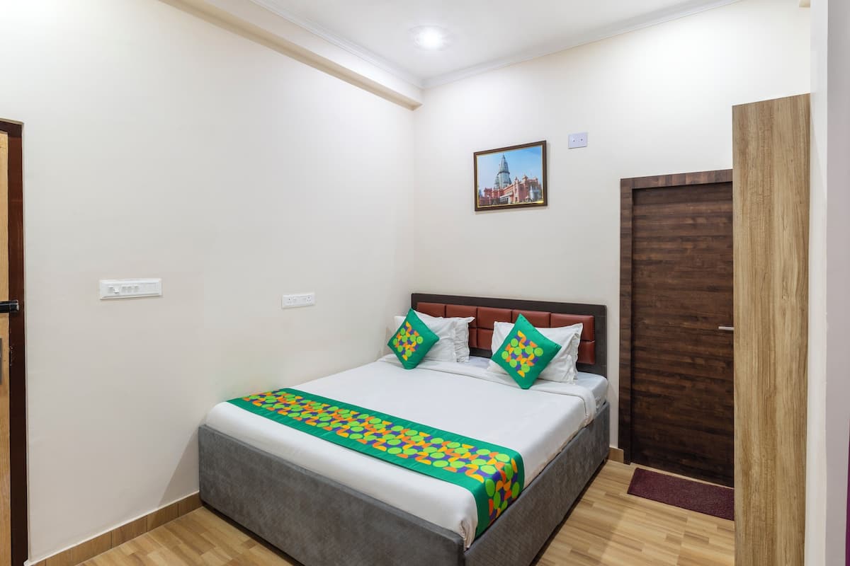 A neatly made bed with a colorful blanket, a wooden headboard, and two pillows with a geometric pattern.