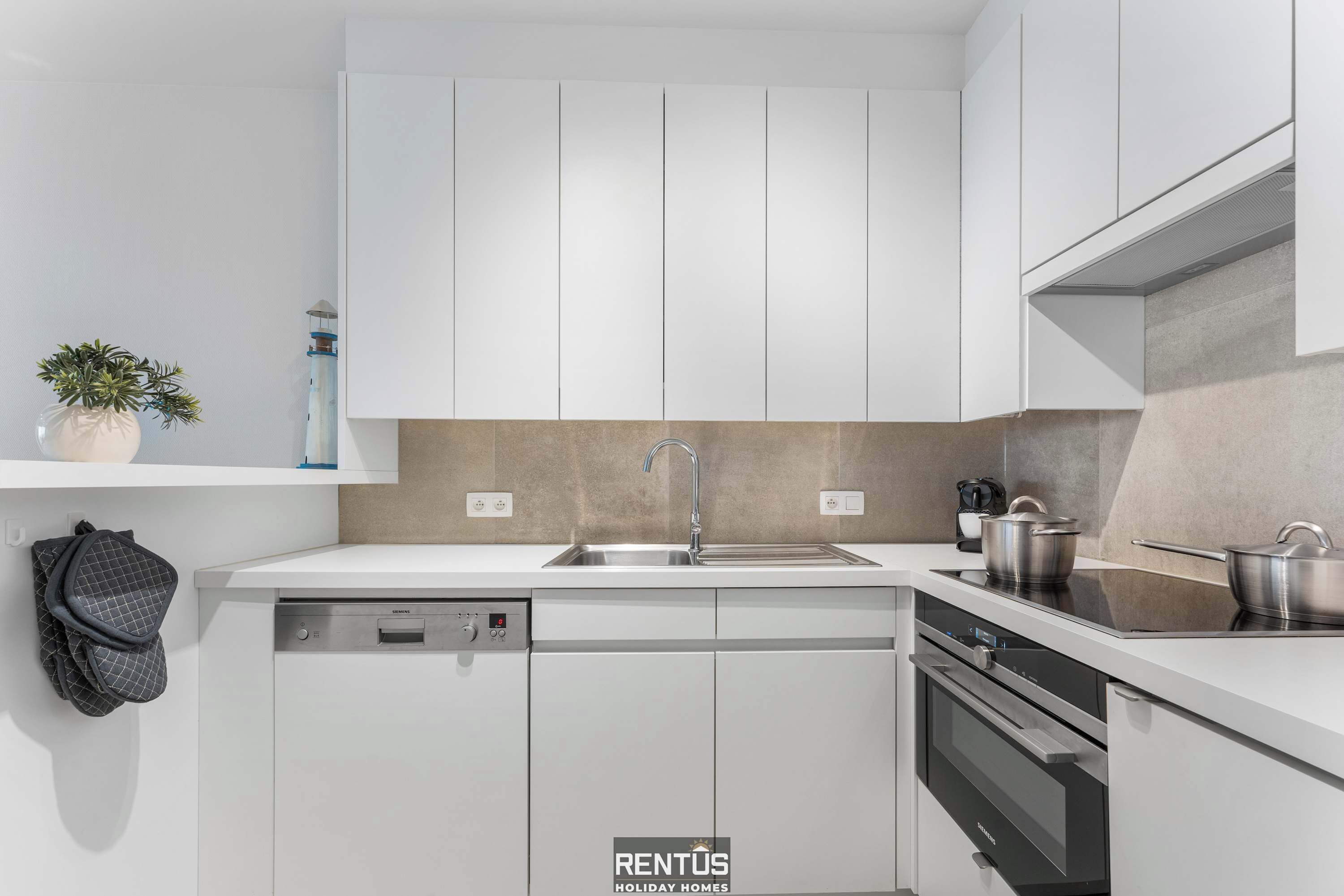Een moderne keuken met witte kasten, een vaatwasser, een oven en een spoelbak.