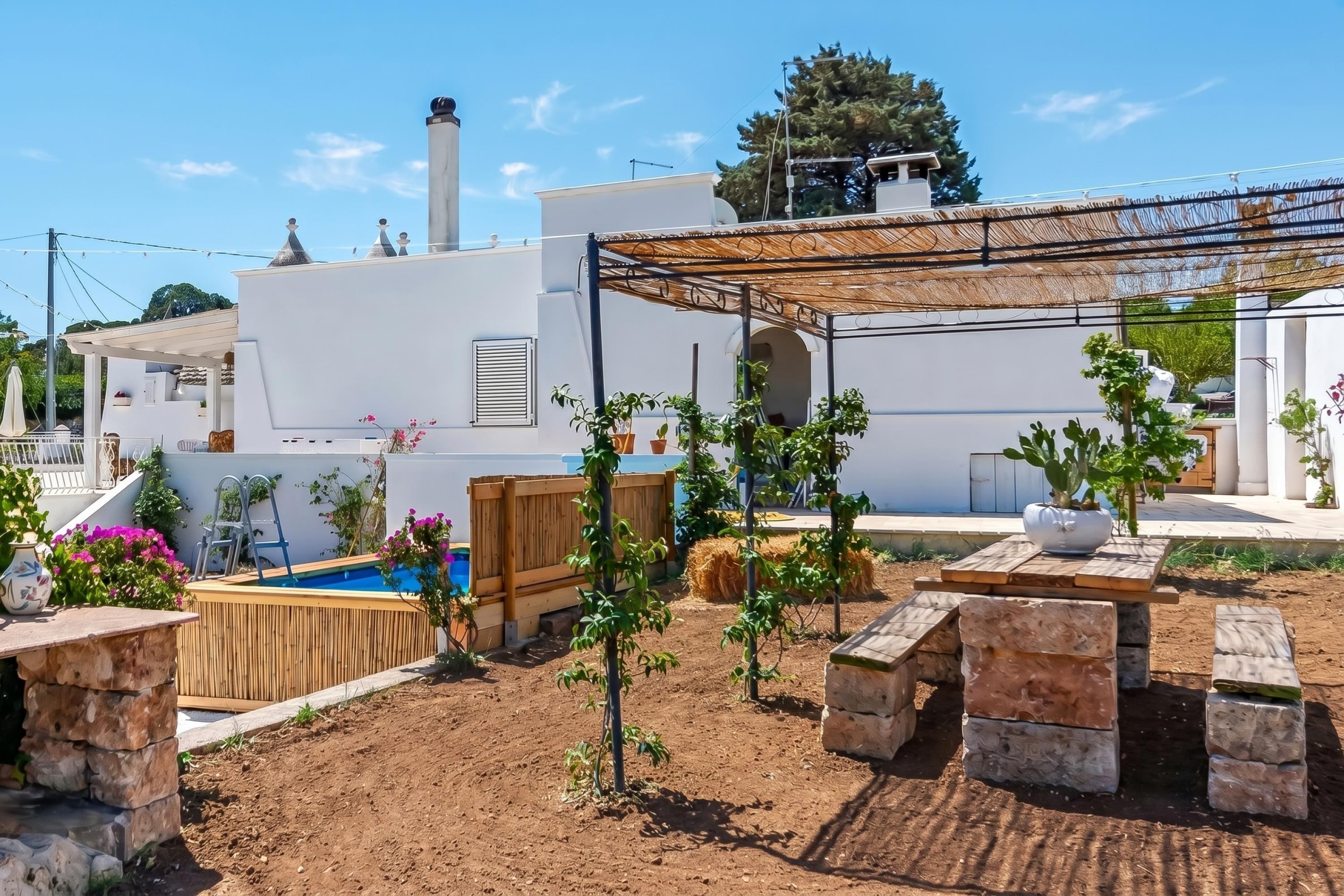 Zona residencial con piscina, mobiliario exterior y una pérgola.