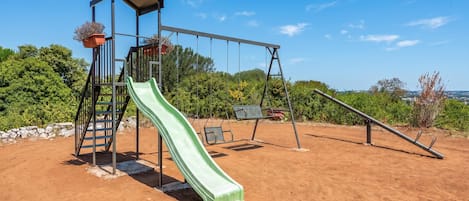 Un parque infantil con tobogán, columpios y una estructura para escalar.