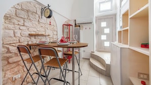 Une cuisine compacte avec un mur en pierre, une table ronde avec des chaises et un four encastré.