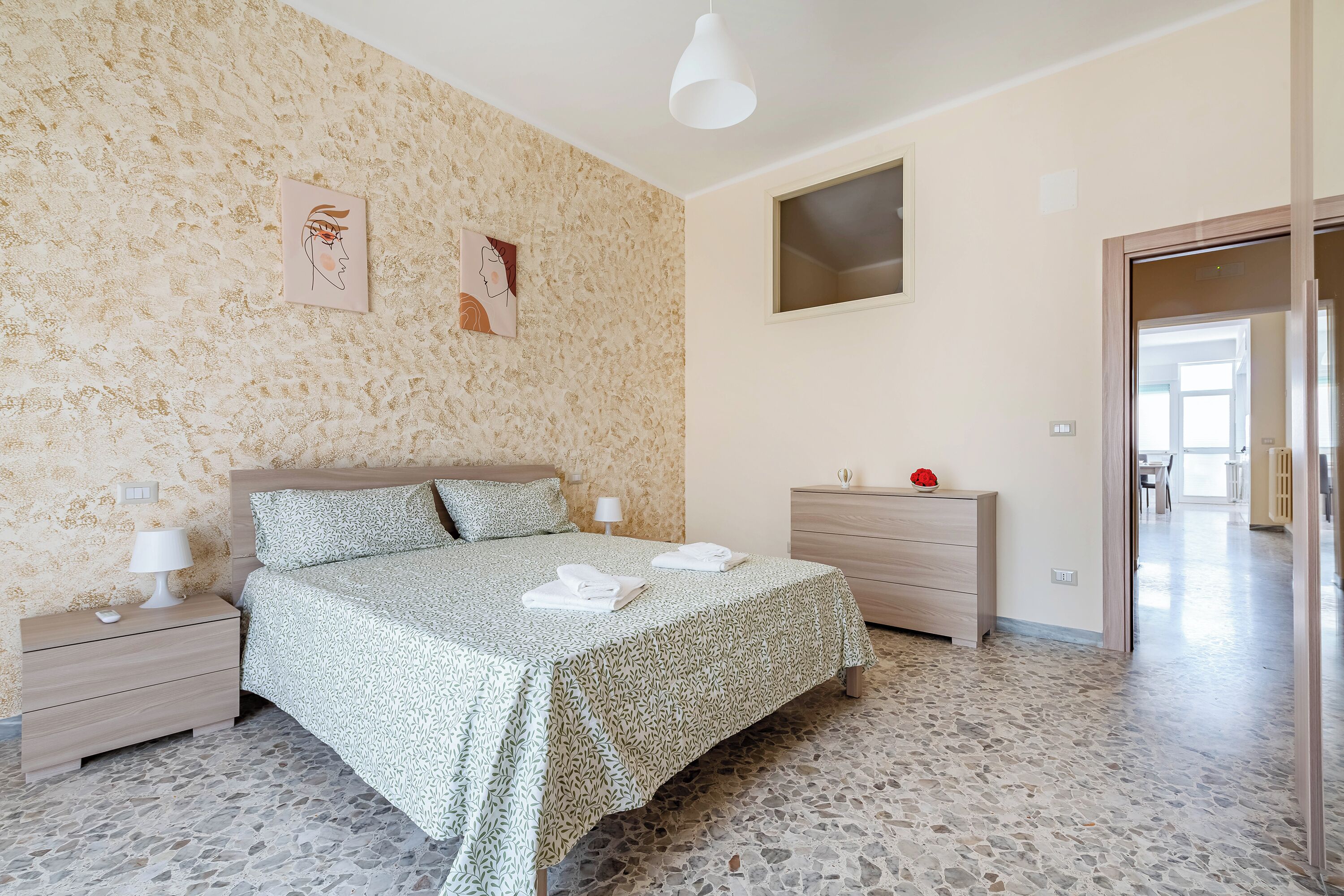 A bedroom with a bed, bedside tables, a dresser, and artwork on the wall.