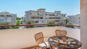 A balcony with wicker chairs and a table, overlooking a residential area with multi-story buildings. - Casa Nonna Caterina Monopoli (Monopoli)
