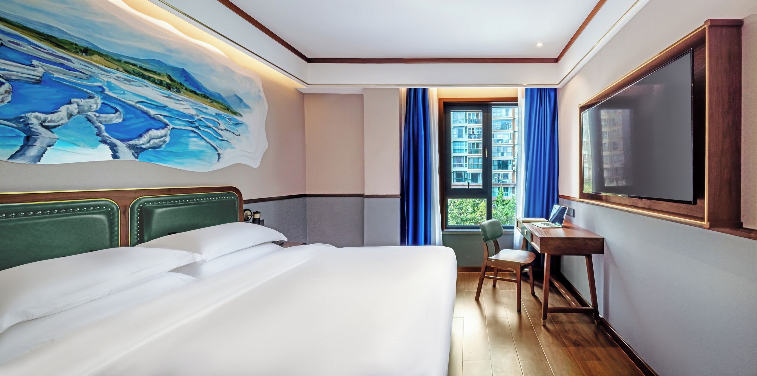 A hotel room with a large bed, a desk with a chair, a TV, and a painting on the wall.