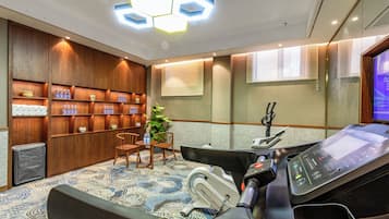 A modern room with a massage table, wooden shelving with toiletries, a small table with chairs, and a large window with blinds.