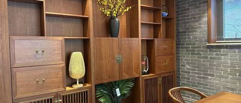 A wooden cabinet with multiple compartments, a vase with yellow flowers, and a potted plant.