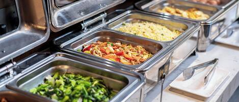 A buffet with multiple food stations including vegetables, rice, and meat dishes.
