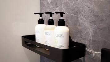 A black shelf with three white bottles of 'Herborist' balancing body shampoo and wash.
