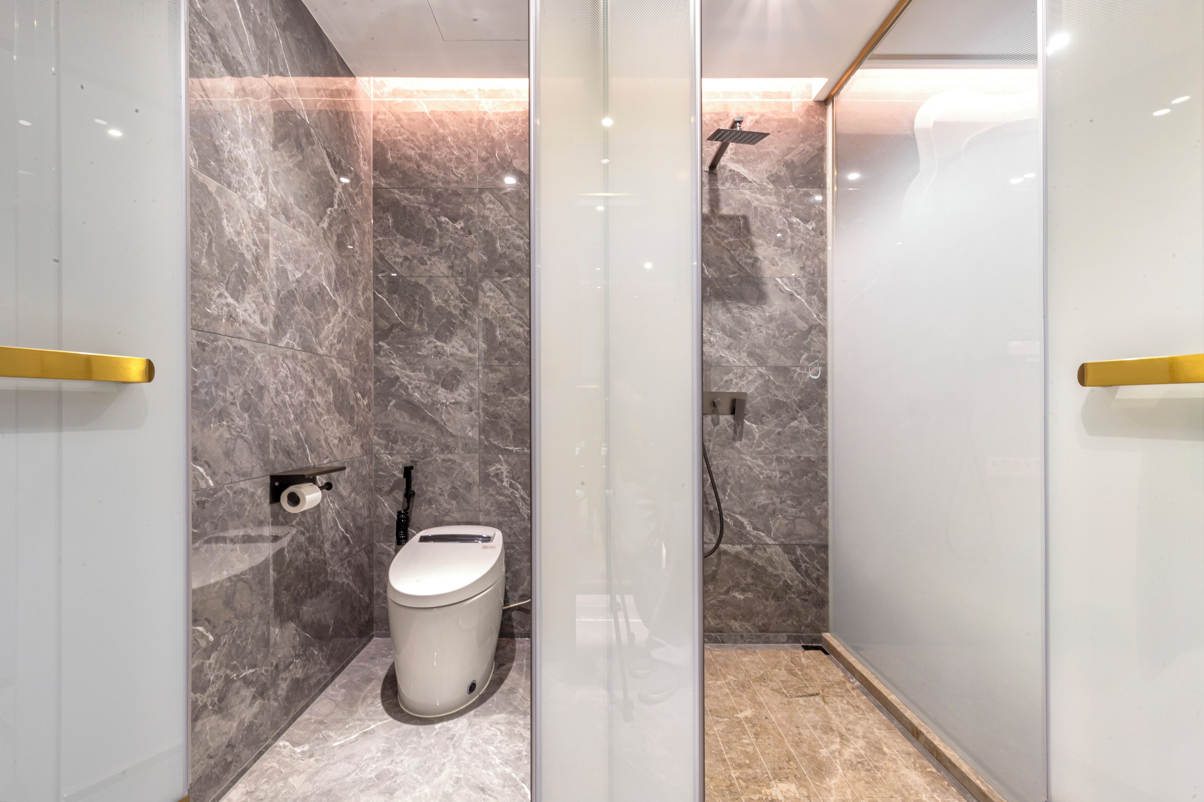 Egy modern fürőszoba márványburkolatú falakkal, WC-vel és külön zuhanyzóval.