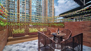 Une terrasse sur le toit, aménagée avec des meubles en osier, des plantes en pot et offrant une vue sur les gratte-ciel.