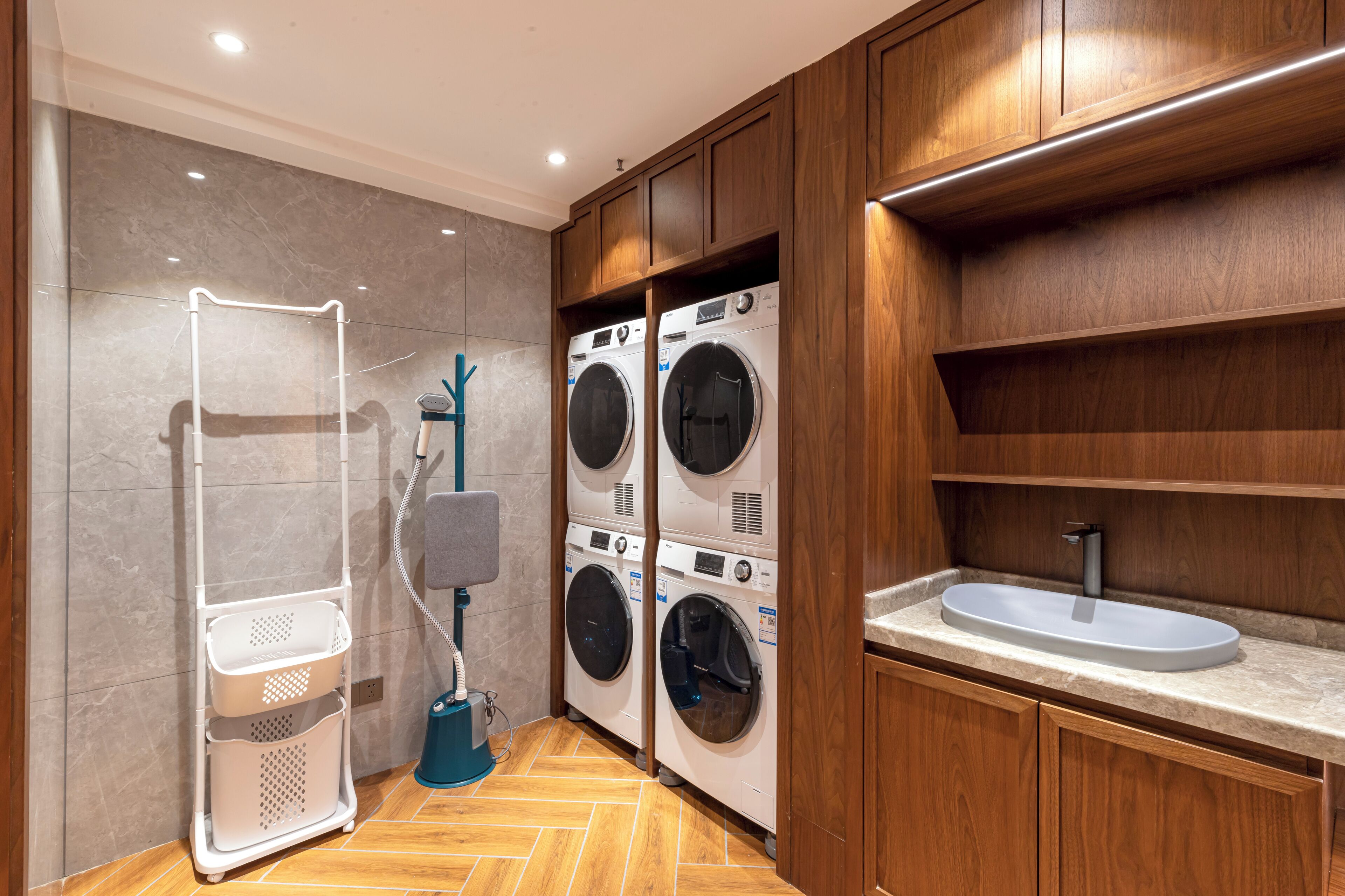 Une buanderie moderne équipée d’un lave-linge et d’un sèche-linge encastrés, d’un évier et d’un étendoir.