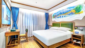 Camera d'albergo con un letto di legno, una scrivania con una sedia, un comodino e un'ampia finestra con tende.
