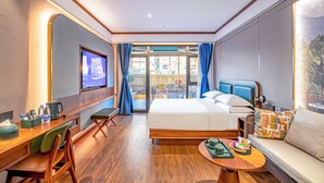 Une chambre d’hôtel comprenant un lit, un bureau avec une chaise, une petite table avec un plateau, une télévision et un balcon donnant sur des immeubles.