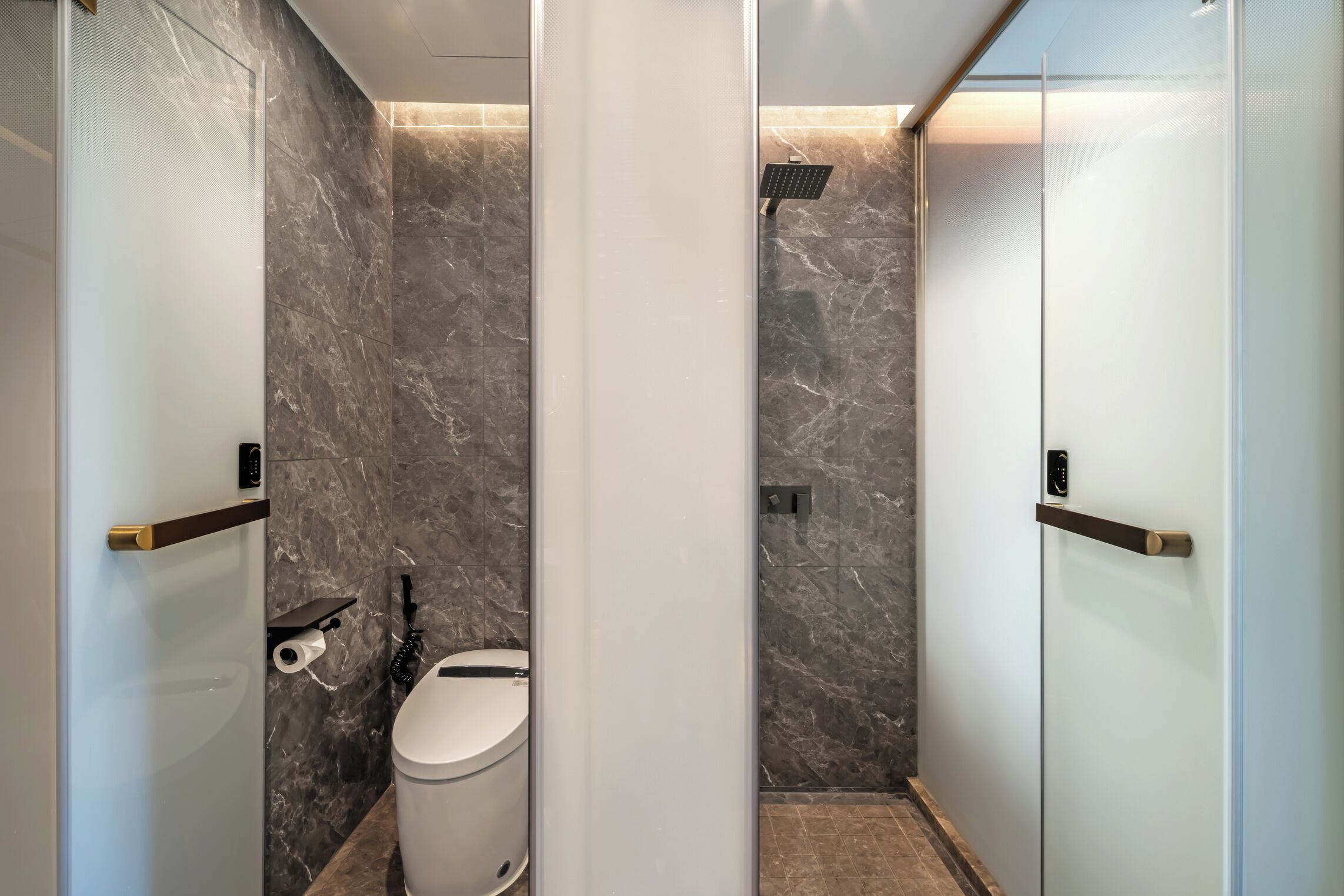 A modern bathroom with a toilet, a shower, and a glass partition.
