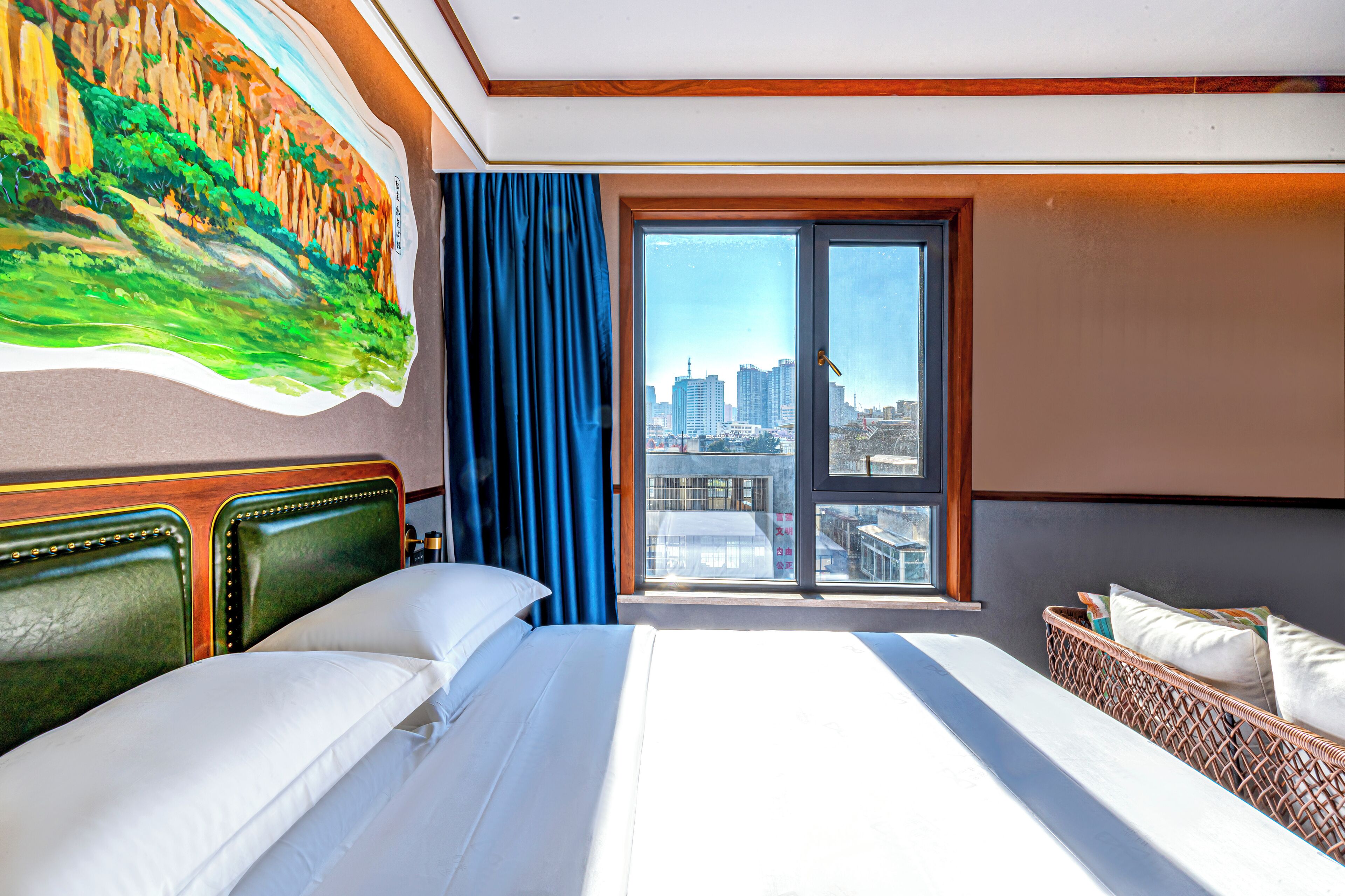 A hotel room with a large bed, a view of the city through a sliding glass door, and a painting on the wall.