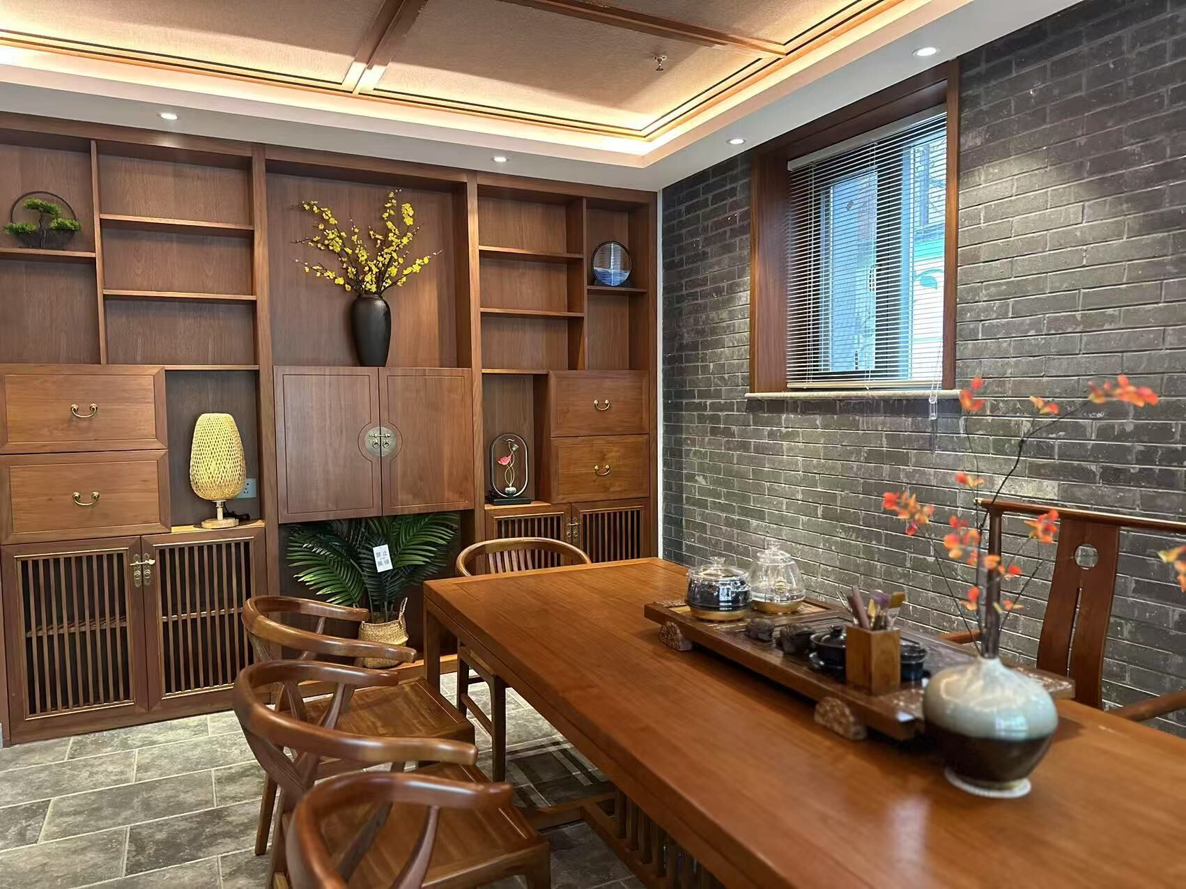 A dining area with a wooden table, chairs, and a brick wall.