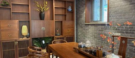 A dining area with a wooden table, chairs, and a brick wall.