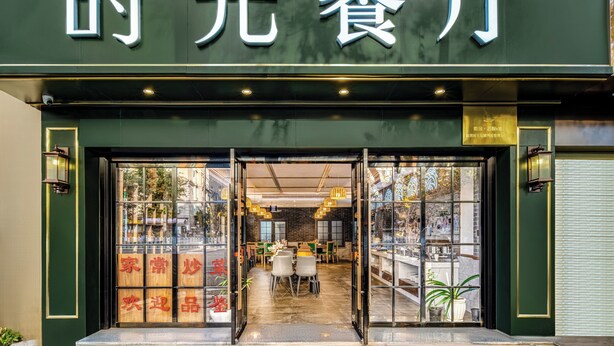 L’entrée d’un restaurant avec une façade verte et une enseigne en caractères chinois.