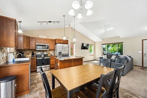 A modern kitchen with wooden cabinets, stainless steel appliances, and a dining area with a wooden table and chairs.