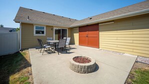 A residential building with a covered patio, a fire pit, and a garage.