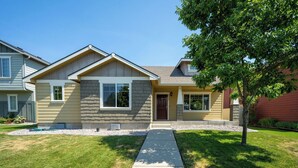 A two-story house with a front yard, a driveway, and a tree.