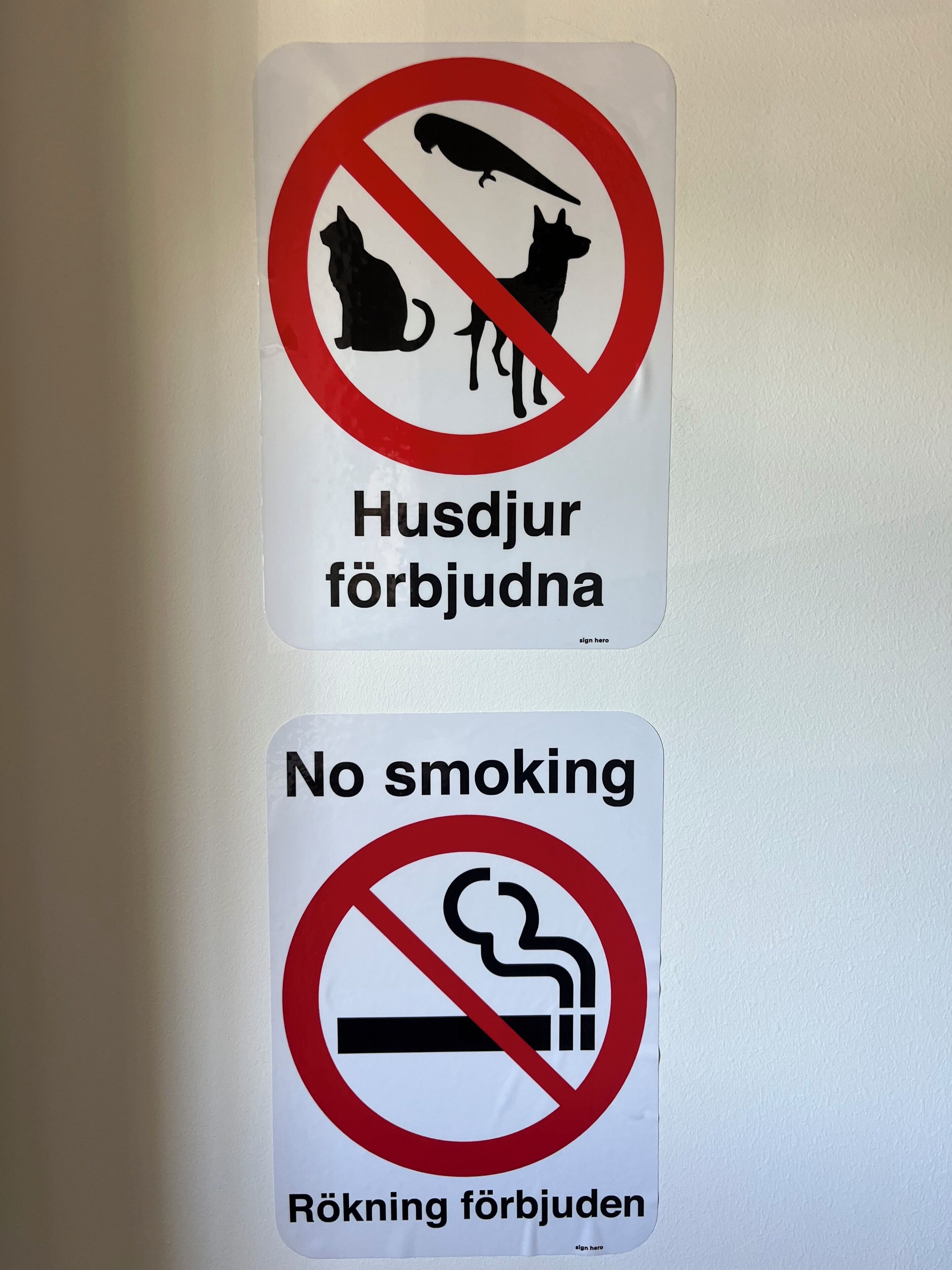 Dos letreros: uno prohíbe perros y el otro, fumar.