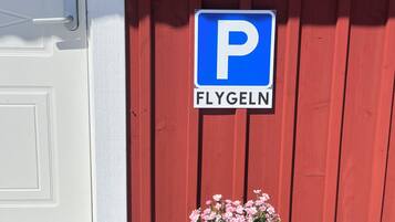 En röd byggnad med en vit dörr, en skylt som förbjuder rökning och en parkeringsskylt.