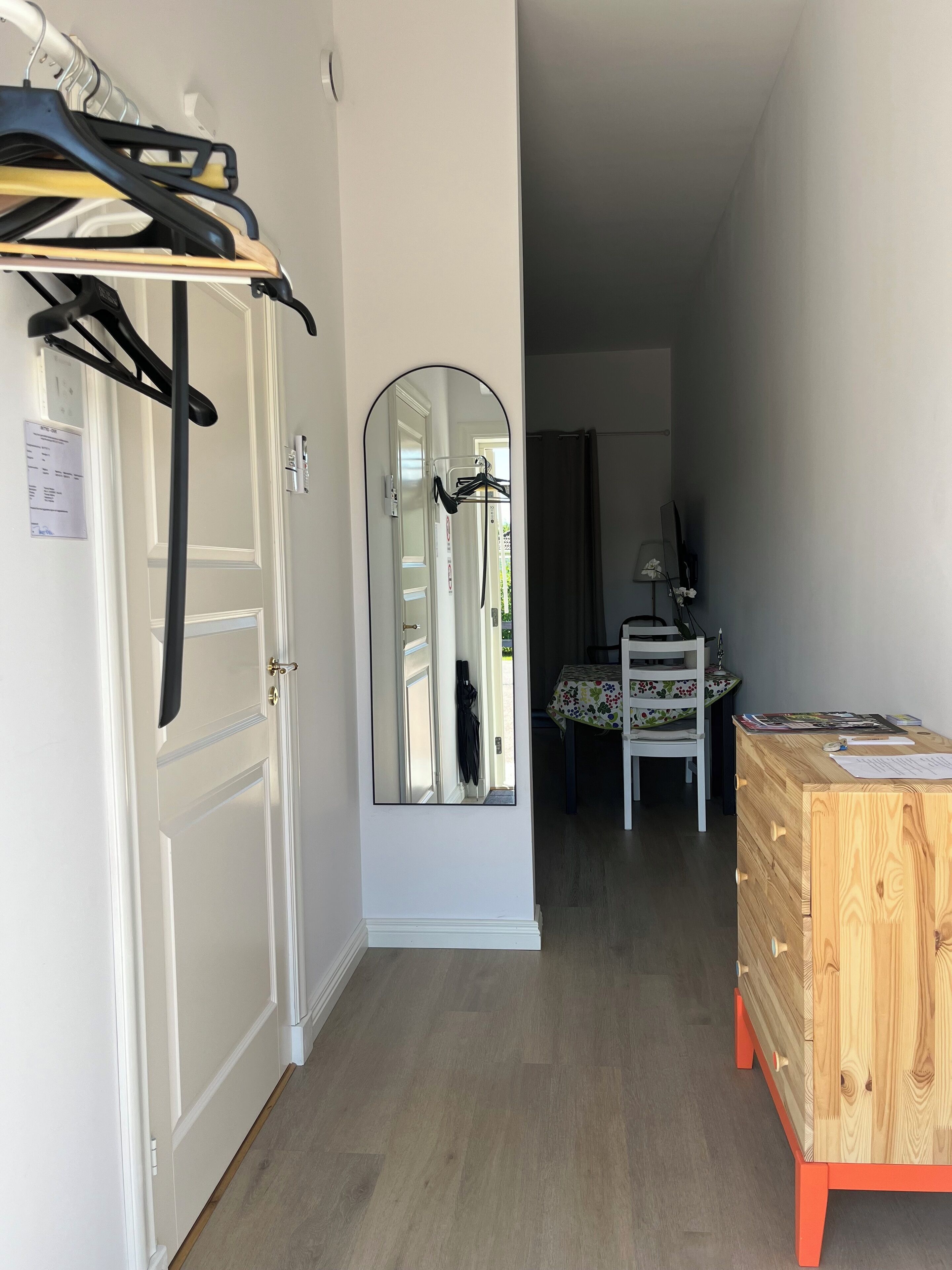 A hallway with a wooden dresser, a mirror, and a coat rack.