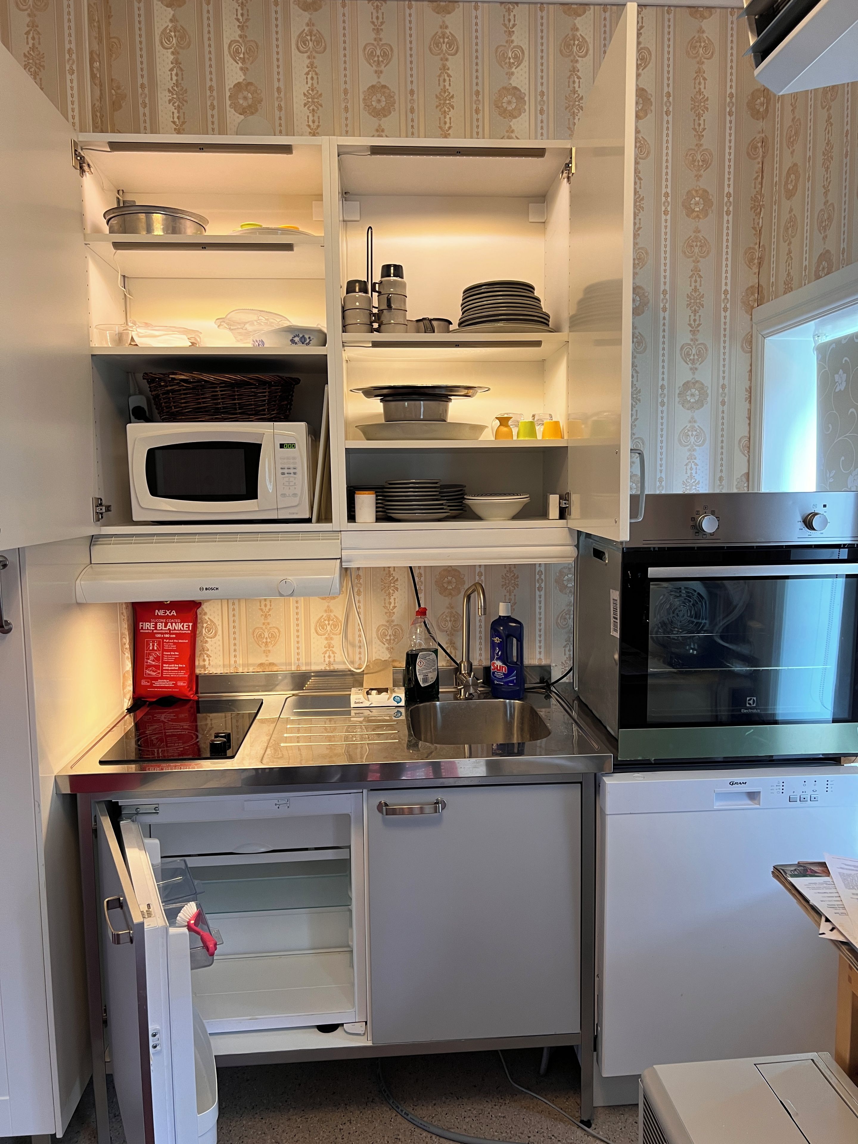 A compact kitchen with a microwave, oven, and refrigerator.