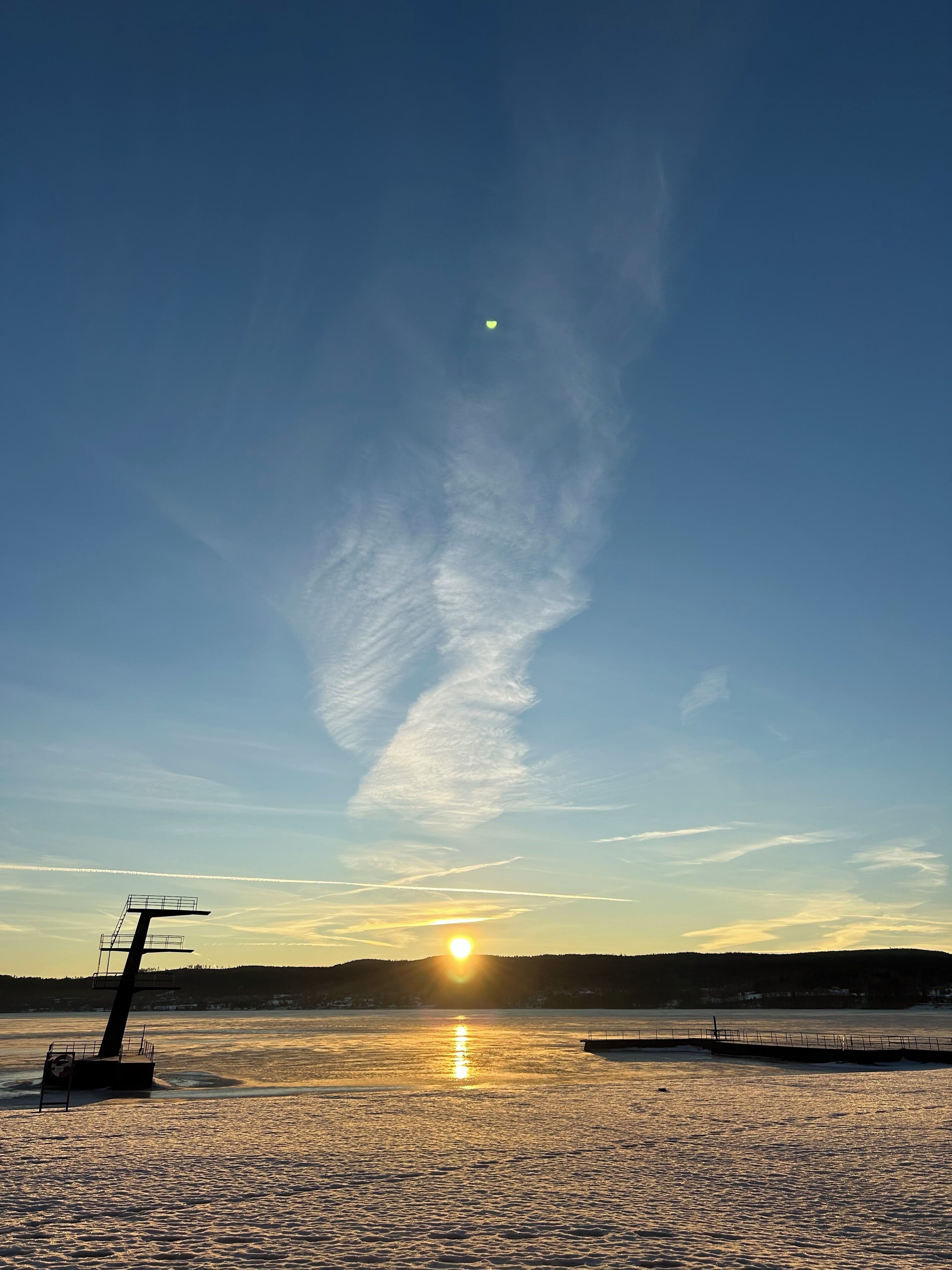 A sunset over a calm body of water with a pier and a boat dock.