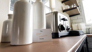 Een keukentafel met witte keramieken flesjes, een retro toaster en een kaartje met de tekst 'The Best wishes to you'.
