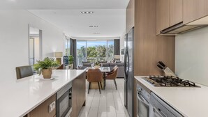 Uma cozinha moderna com uma ilha central, uma sala de jantar com sofá e vista para o exterior.