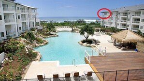 A resort with a central swimming pool, lounge areas, and ocean views.